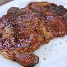 two pieces of meat on a white plate with parsley sprinkled on top