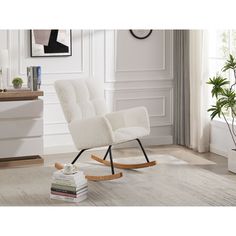 a white rocking chair sitting on top of a wooden floor next to a potted plant