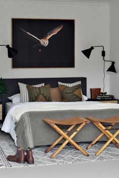 a bedroom with a bed, two chairs and a painting on the wall above it