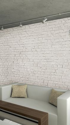 a living room with white couches and a brick wall in the backround