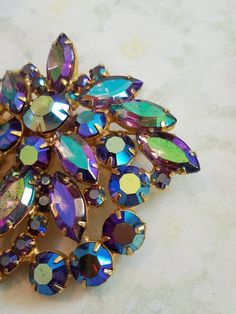 This is a vintage gold tone metal brooch. It has blue/green/purple iridescent rhinestones. There are some /scratches marks on the stones due to age and normal use. The price reflects this. The brooch measures a bit over 2.5 x 2.25 inches. Don't forget to stop in at my other Etsy shop... http://www.etsy.com/shop/xtdesigns. Follow me on Twitter at... MyYiayiaHadThat@MyYiayiaHadThat. If you have a wish list or are looking for something specific, please ask. I may have exactly what you are looking f Black Opal Engagement Ring, Crystal Glassware Antiques, Antique Costume Jewelry, Jewelry Knowledge, Vintage Rhinestone Jewelry, Vintage Rhinestone Brooch, Vintage Sterling Silver Rings, Antique Brooches, Pin Jewelry