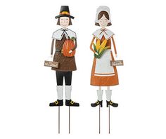 two wooden scarecrows holding pumpkins and corn on the cob