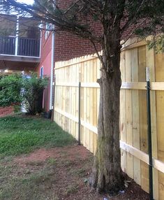 a wooden fence next to a tree in front of a building