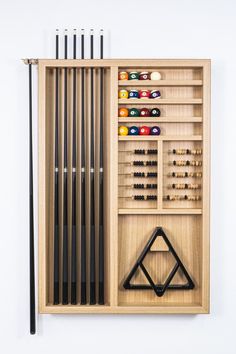 a wooden case with pool balls, cues and cues in it on a white wall