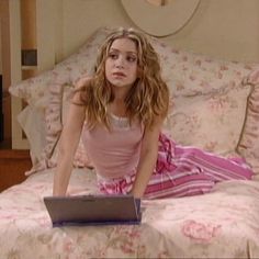 a young woman sitting on top of a bed with a laptop computer in her hand