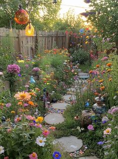 a garden filled with lots of flowers next to a wooden fence and light fixture hanging from the ceiling