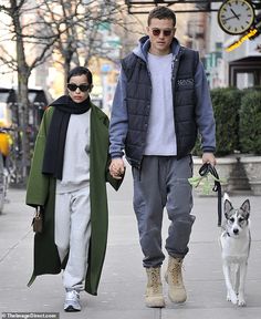 a man and woman are walking their dog down the street with one holding his hand