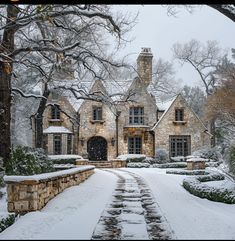 a stone house is covered in snow and surrounded by trees, shrubs and shrubbery