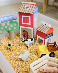 a toy farm with animals, horses and hay in the ground next to a red barn