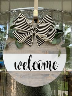 a welcome sign hanging from the side of a glass door with a bow on it