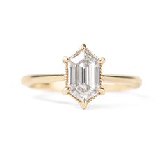 an emerald - cut diamond ring on a white background with the center stone in yellow gold