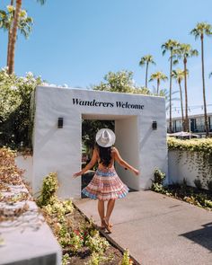 a woman in a dress and hat walking into a welcome sign for wanderrs welcome