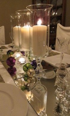 a table topped with candles and plates covered in christmas decorations on top of a tabletop