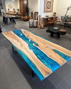 a table made out of wood with blue paint on the top and bottom, sitting in a room filled with furniture