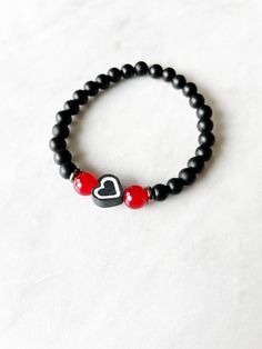 OVERVIEW **This heart bracelet is made with 6mm matte black beads, 6mm red glass beads, and a black polymer clay heart bead, set on stretchy cord. Approx. 7 inches ** Custom designed and made in USA. LOOKING TO STACK YOUR BRACELETS? More bracelets can be found here: https://www.etsy.com/shop/CarbonAndCopper?section_id=18041311 SHIPMENT & DELIVERY **All jewelry comes in a custom linen bag and shipped in a white padded envelope. **This bracelet is made and ready to be shipped to you within 5-7 days of purchase. **Domestic Shipping is approximately 3-5 business days using USPS First Class Mail **For more Shipping information, please see link below: https://www.etsy.com/shop/CarbonAndCopper?ref=hdr§ion_id=18041311#policies OTHER INFO ** Please keep in mind there may be some variation in the co Adjustable Black Bracelets For Valentine's Day, Adjustable Black Heart-shaped Bracelet, Adjustable Black Heart Bracelets, Black Friendship Bracelet For Valentine's Day, Handmade Black Bracelets For Valentine's Day, Handmade Black Bracelet For Valentine's Day, Black Heart-shaped Adjustable Beaded Bracelets, Adjustable Beaded Black Heart Bracelet, Adjustable Black Beaded Heart Bracelet