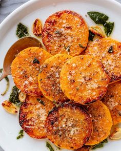 a white plate topped with sliced oranges covered in parmesan cheese and herbs