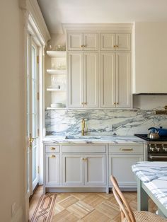 a kitchen with white cabinets and marble counter tops