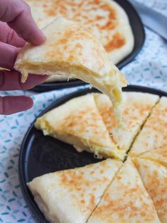 someone is dipping cheese on top of cheesy bread in a black plate with blue and white napkins