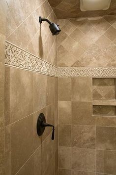 a walk in shower sitting next to a tiled wall and floor covered in beige tiles