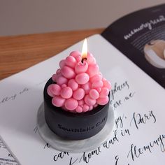 a small pink candle sitting on top of a table next to an open book with writing