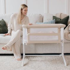 a woman sitting on a couch next to a baby crib