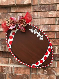 a football shaped door hanger on the side of a brick wall with a bow