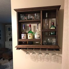 a wooden shelf with wine glasses and liquor bottles on it, hanging from the wall