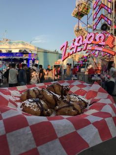 doughnuts are sitting on a checkered paper in front of an amusement park