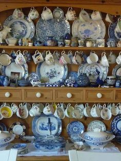 a display case filled with lots of blue and white plates on top of wooden shelves