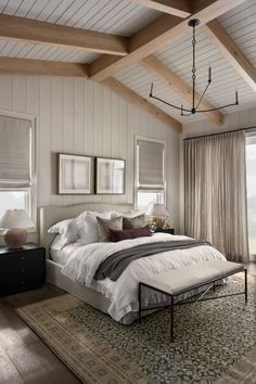 a bedroom with white walls and wood beams