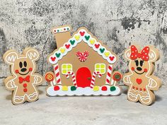 two wooden gingerbread houses with mickey and minnie mouse decorations on them, one has a red bow