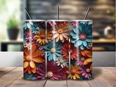 three colorful flowers are on the side of a metal container with two straws in it