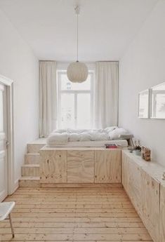 a bedroom with white walls and wooden floors, along with a bed that has been built into the wall