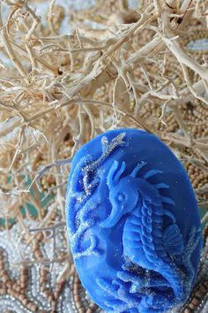 a blue sea urn sitting on top of a sandy beach next to dry plants