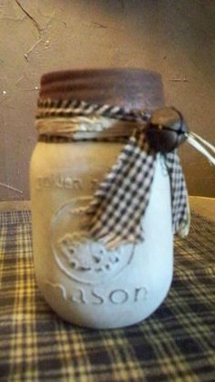 a mason jar sitting on top of a checkered table cloth with a ribbon tied around it