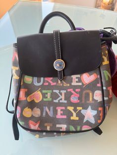 Dooney & Bourke Bags | Dooney Bourke Doodle Backpack Black Multicolor  Black MINT, RARE IG546 BB BACKPACK 41296040 About 9.5" x 12" Features: SILVER Toned Hardware.  Inside pockets, Adjustable strap. We are passionate about antiques, collectables, vintage and anything with an interesting story or history. We have been collecting for years and are enthusiastic about all genres, periods and styles. Fell free to make offers, Message us with any questions. Antique and Vintage items to live with and use today, and pass down tomorrow - value always!  Offering pretty and useful antique and vintage items that keep or increase their value -your money always well-spent! You can be sure your item will be packaged with great care We ship within the Continental US. We take credit cards. Thank you. **ST Dooney And Bourke Handbags Dooney & Bourke, Dooney And Bourke Disney Vintage, Dooney Bourke Shoes, Dooney & Bourke Bags Dooney & Bourke, Dooney Bourke Nylon Handbags, Interesting Story, Dooney & Bourke Bags, Black Backpack, Dooney Bourke