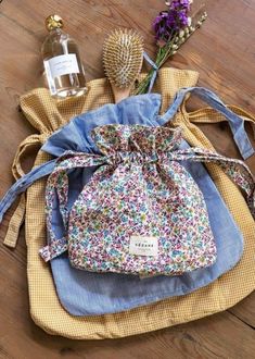 a small bag sitting on top of a wooden floor next to a bottle and flowers