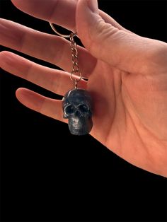 a hand holding a black skull keychain on it's palm with a ring around it