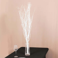 there is a vase with branches in it and two wine glasses on the table next to it