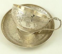 a silver cup and saucer on a white table