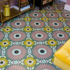 a living room with yellow furniture and colorful floor tiles on the floor, along with an area rug that looks like a flower pattern