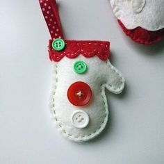 two christmas ornaments are sitting on a white surface, one is red and the other is green