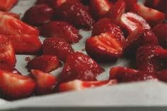 sliced strawberries are sitting on a white tray