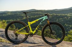 a yellow and blue mountain bike sitting on top of a rock