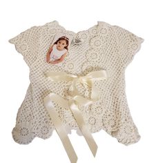 a baby's christ gown with a ribbon around it and a photo on the front