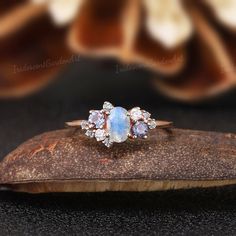 a blue and white stone ring sitting on top of a wooden piece with flowers in the background