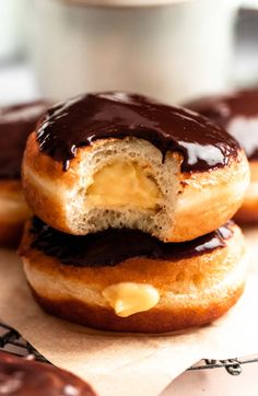 chocolate covered doughnuts sitting on top of each other next to a cup of coffee