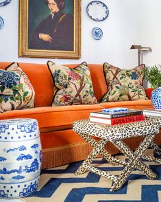 a living room with an orange couch and several blue and white vases on the coffee table