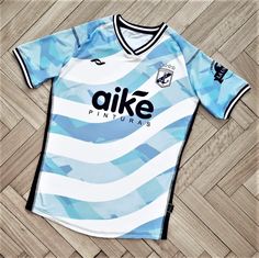 a blue and white soccer jersey sitting on top of a wooden floor