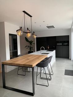 a modern kitchen with an island table and bar stools